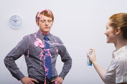 Office worker spraying silly string on colleague