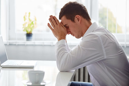 Stressed businessman resting head on hands at desk