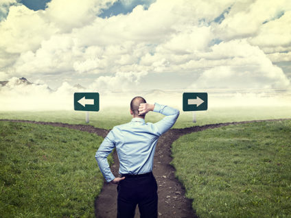 Man scratching head while standing at crossroads