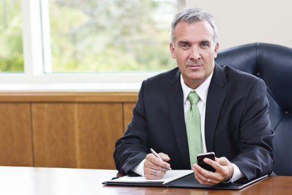 Older businessman sitting at desk holding phone