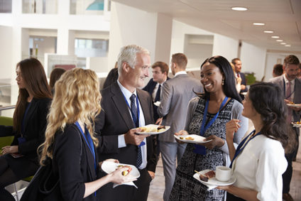 People standing, holding food and talking