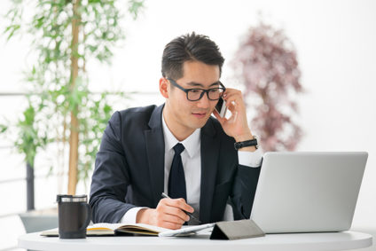 Young businessman using laptop and phone in the office