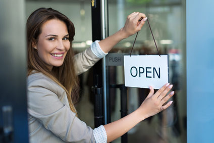 Woman turning door sign to "open"