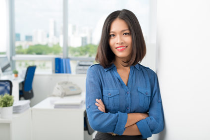 Businesswoman with crossed arms smiling, skyline in background