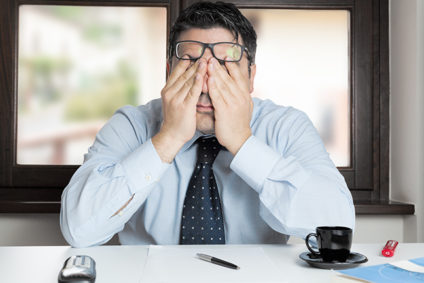 Exhausted man rubbing his eyes under glasses