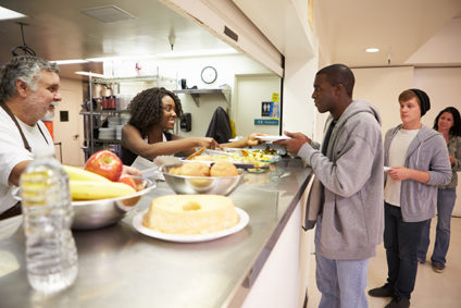 Two volunteers serving meals at a shelter