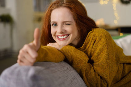 Woman winking and holding thumb up