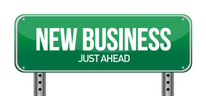 Green road sign reading "New Business Just Ahead"