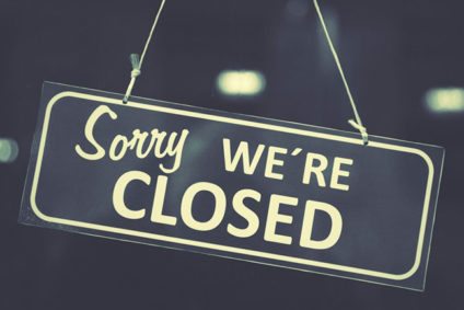 "Sorry WE'RE CLOSED" sign hanging in window