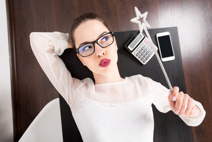Young woman lying on the desk at office and holding magic wand in her hand