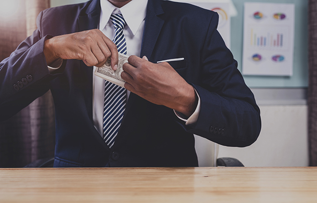 Man putting dollars into suit pocket