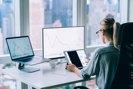 Woman using tablet in front of laptop and desktop