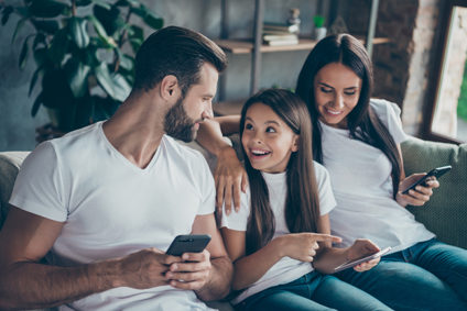 Family of three using smartphones on couch