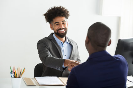 Two men sitting across from each other shaking hands