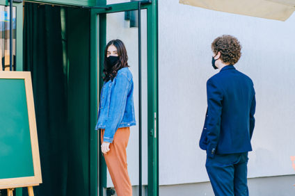 two masked people in a line outside a shop
