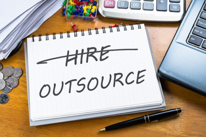notepad with word "hire" crossed out and "outsource" written in underneath